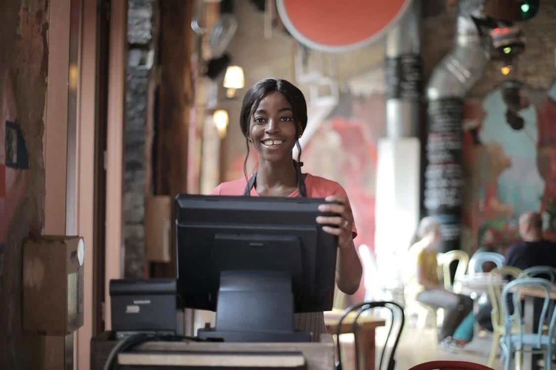 smiling staff member behind cash register