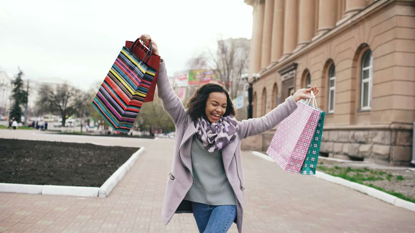 A young woman smiling and holding shopping bags