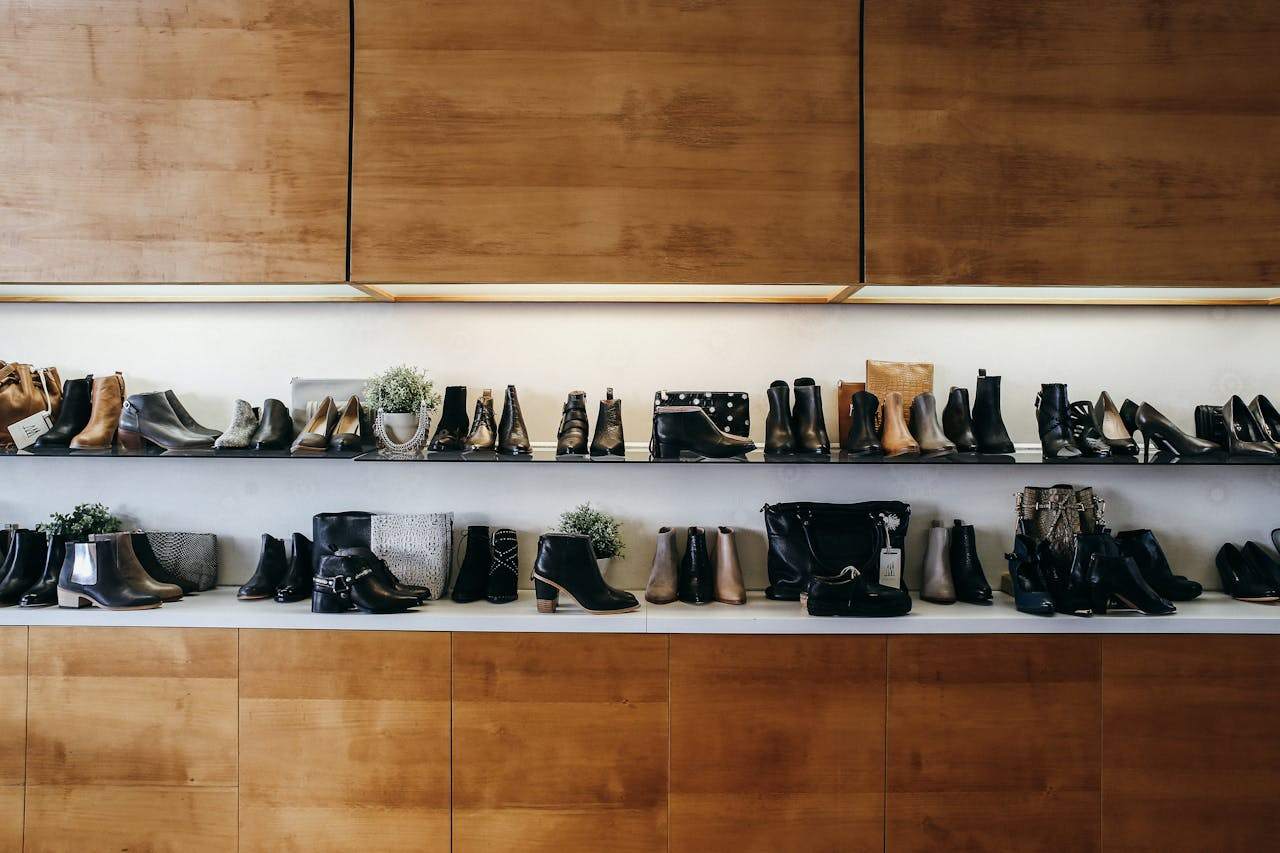 A wide range of shoes displayed on shelves in two layers in a boutique