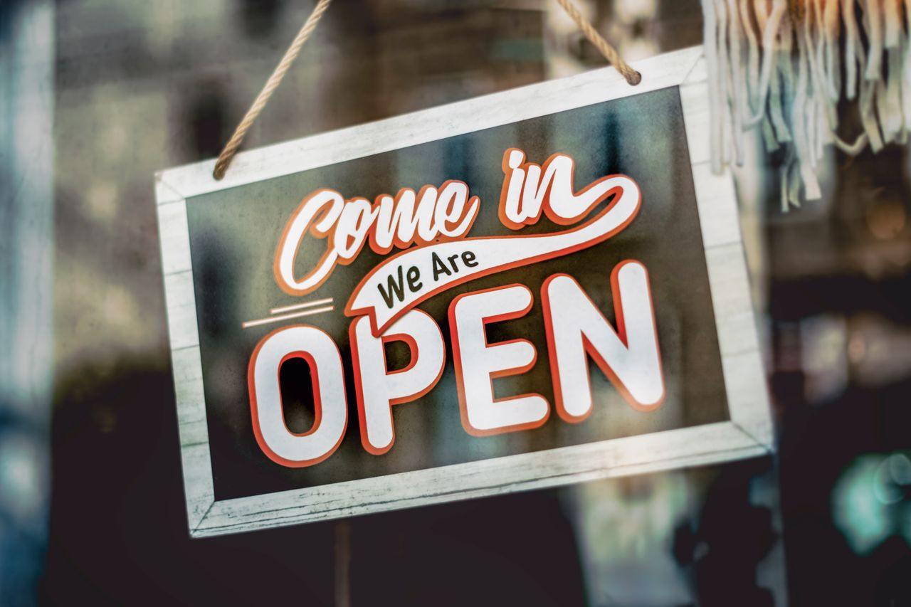 A convenience store window with the sign that reads come in we are open